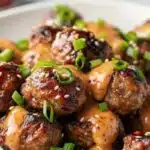 Korean BBQ meatballs with spicy mayo dip, plated with garnishes.